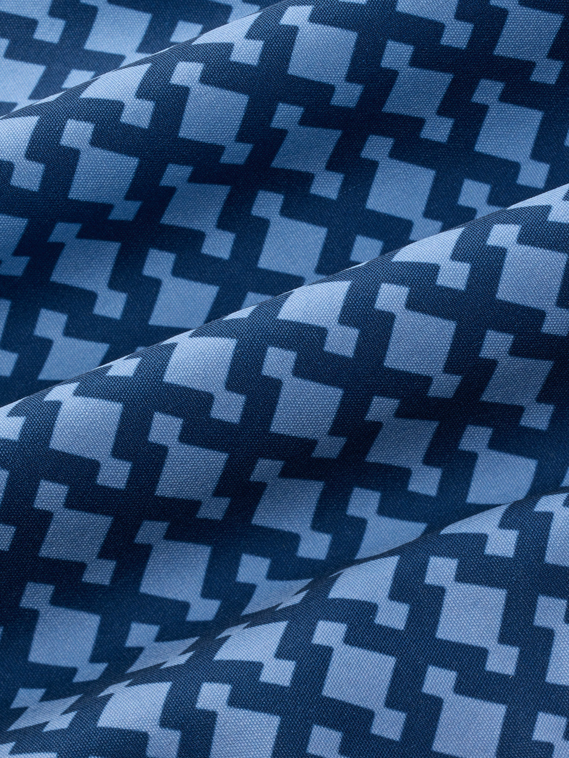 Blue and navy geometric patterned fabric with alternating squares and anchor motifs displayed with natural folds.