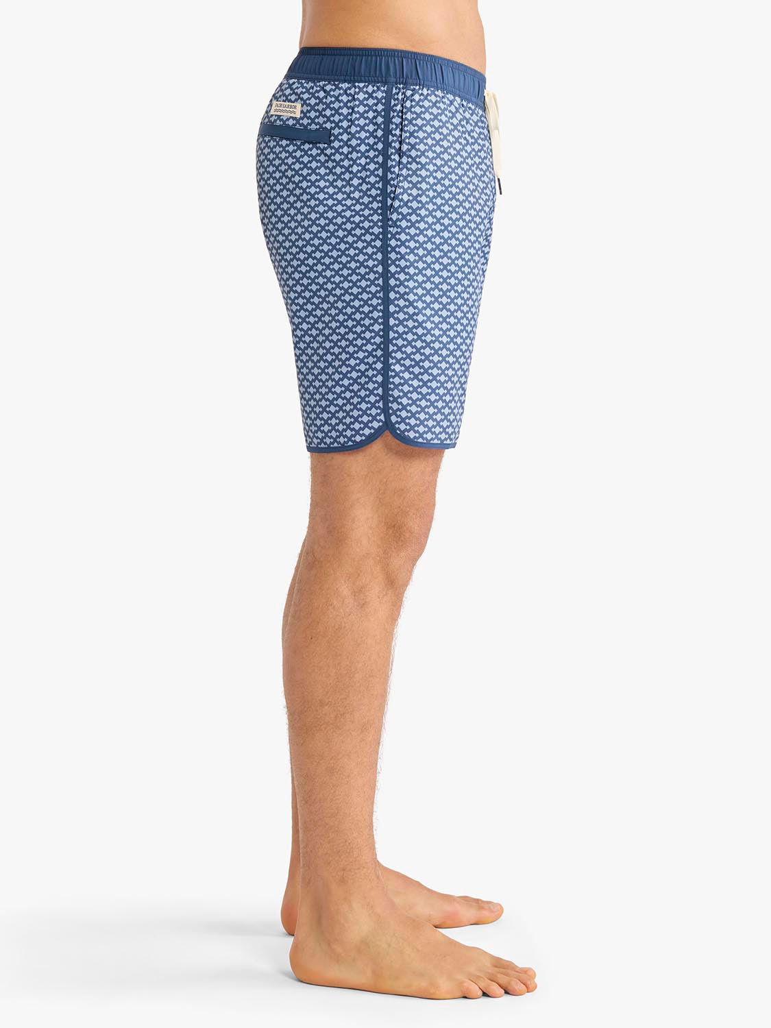 Blue swim trunks with small white anchor pattern and navy waistband displayed on male model.