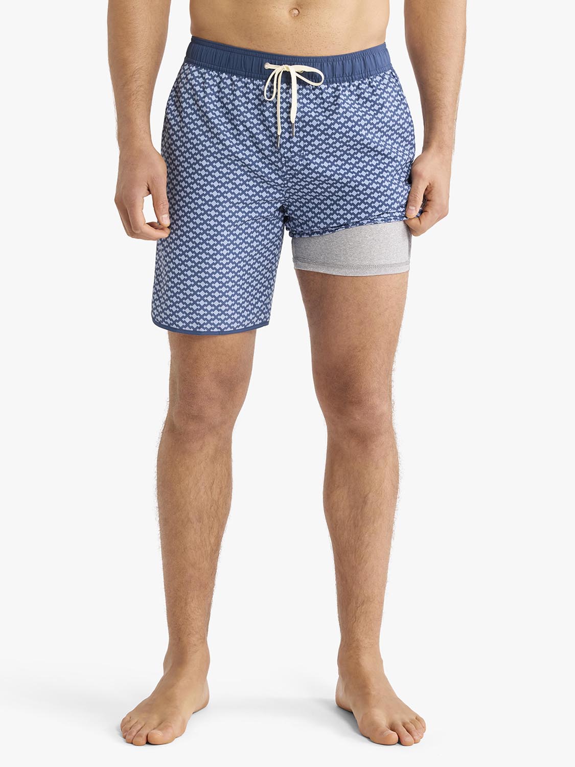 Man wearing blue swim trunks with white anchor pattern and gray leg bands.