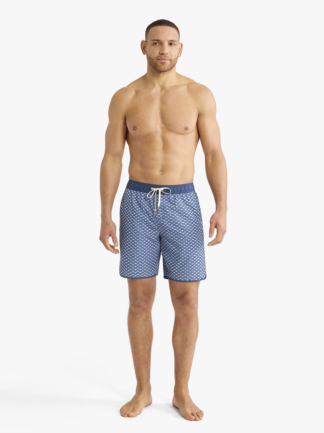 Man wearing blue patterned swim trunks with drawstring waistband and anchor print design.