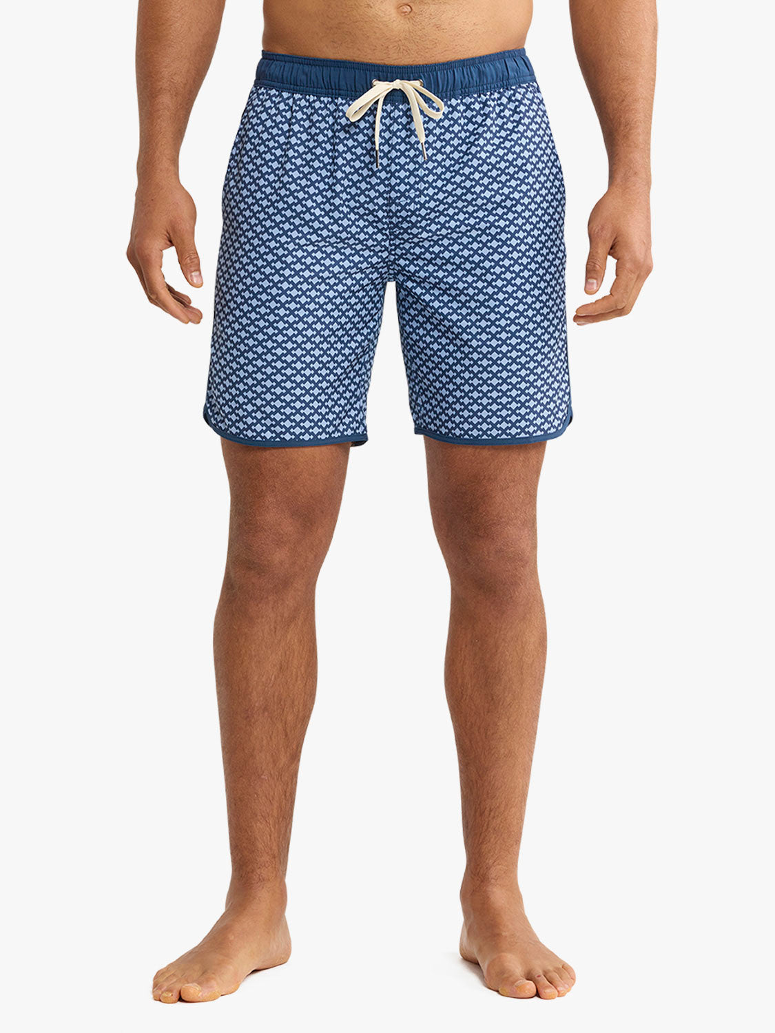 Man wearing blue swim shorts with a small white anchor pattern and cream drawstring waistband.