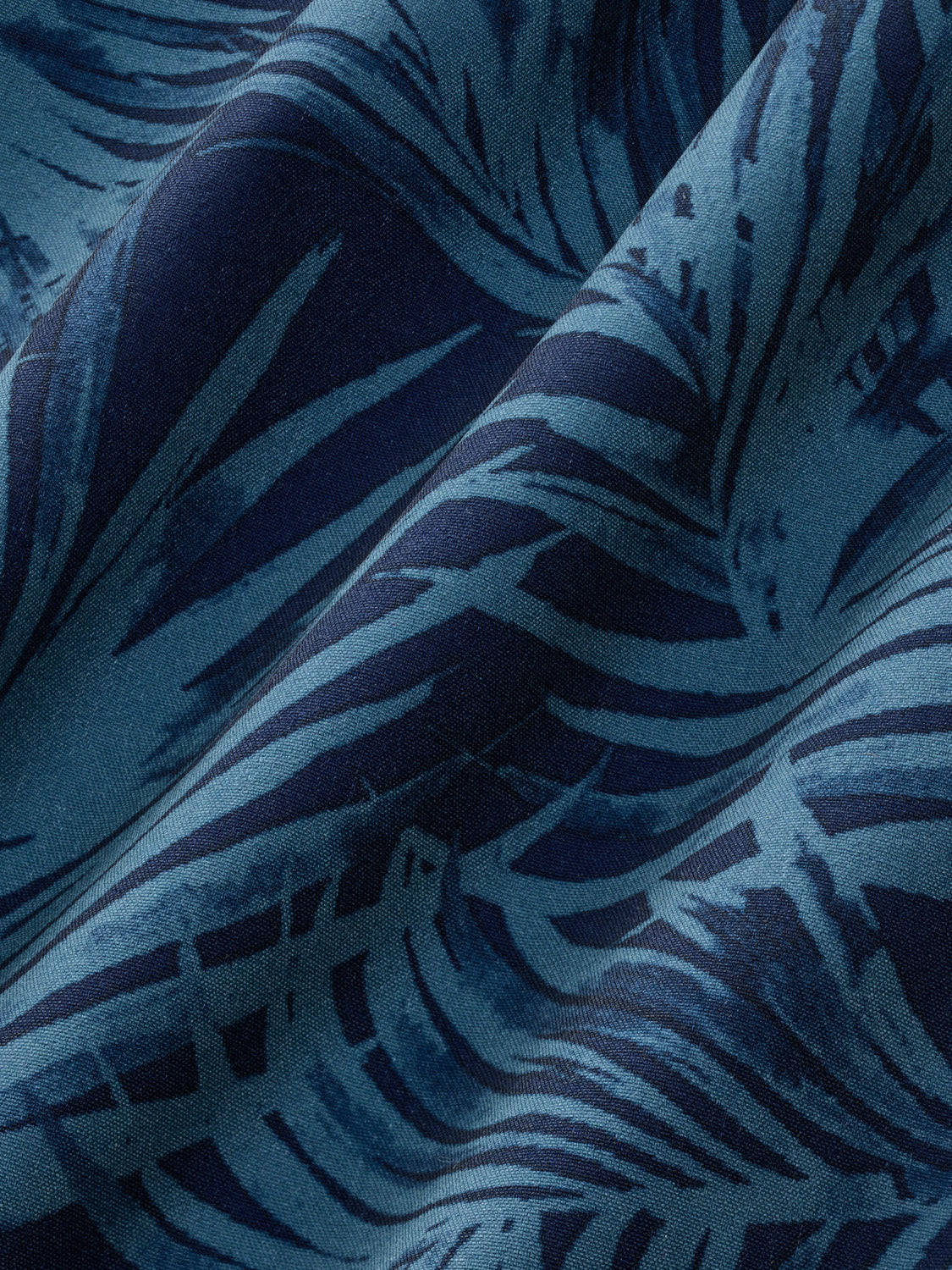 Grey fabric with dark blue and teal floral leaf pattern design displayed at close range.