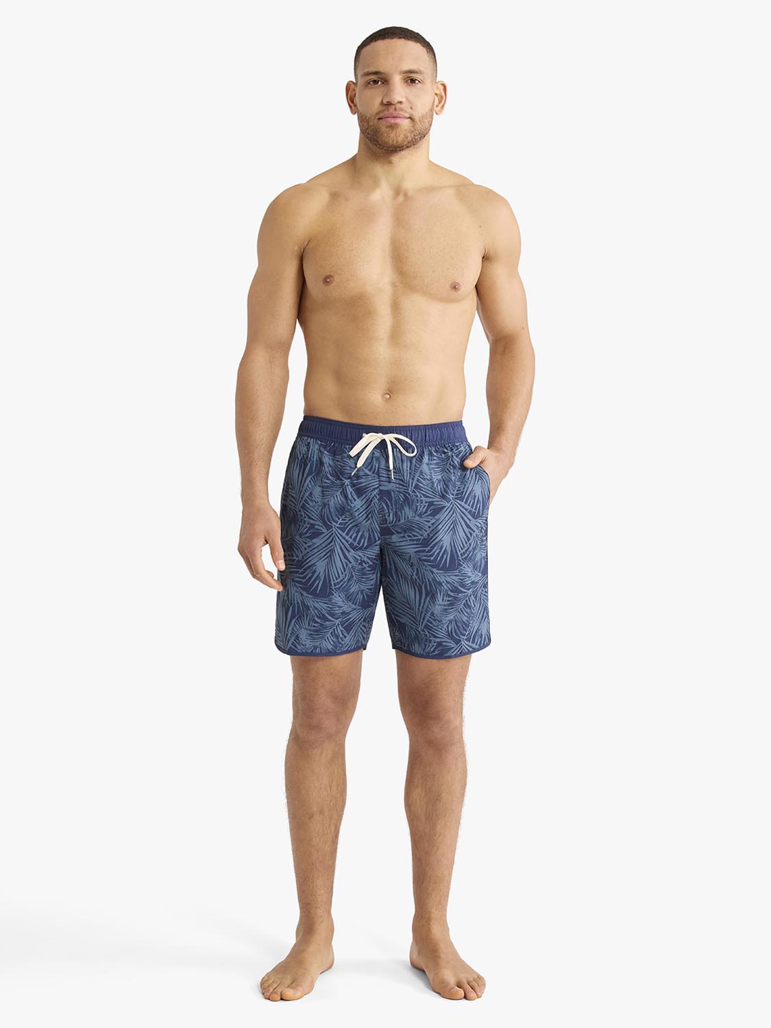 Man wearing navy swim shorts with an all-over floral pattern and drawstring waist.