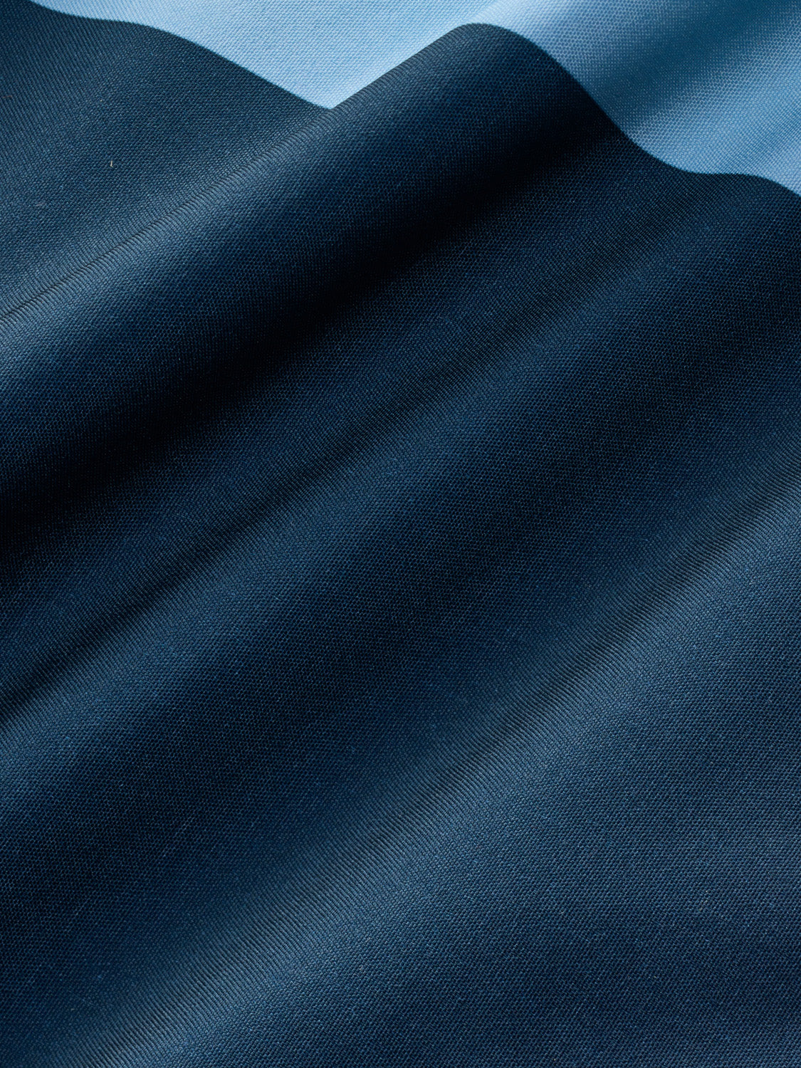 Light blue and dark blue striped fabric with diagonal ribbed texture and natural folds.