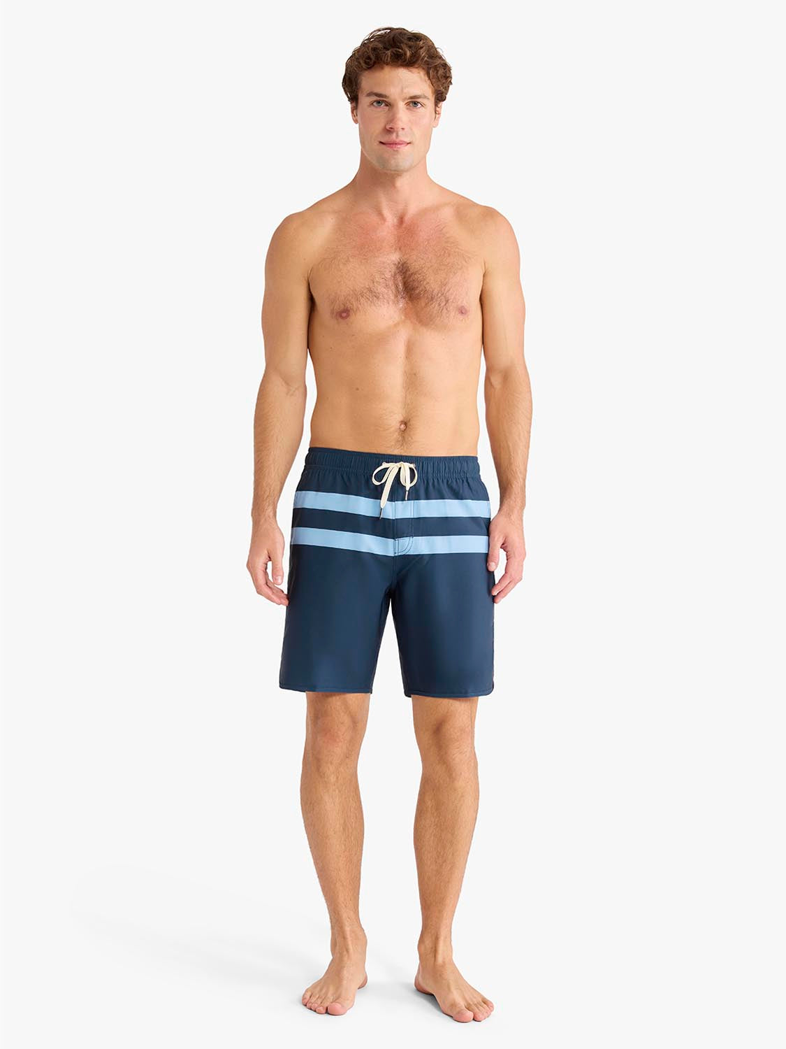 Man wearing navy swim trunks with light blue horizontal stripes and drawstring waistband.