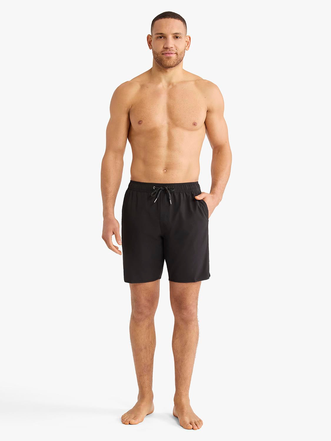 Man wearing black shorts with drawstring waistband and side pockets standing barefoot.