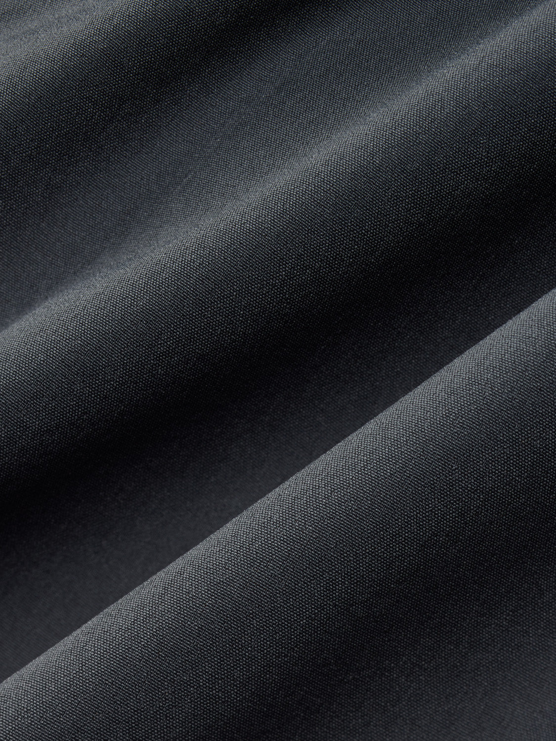 Slate-colored fabric with diagonal folds and a textured woven surface pattern.