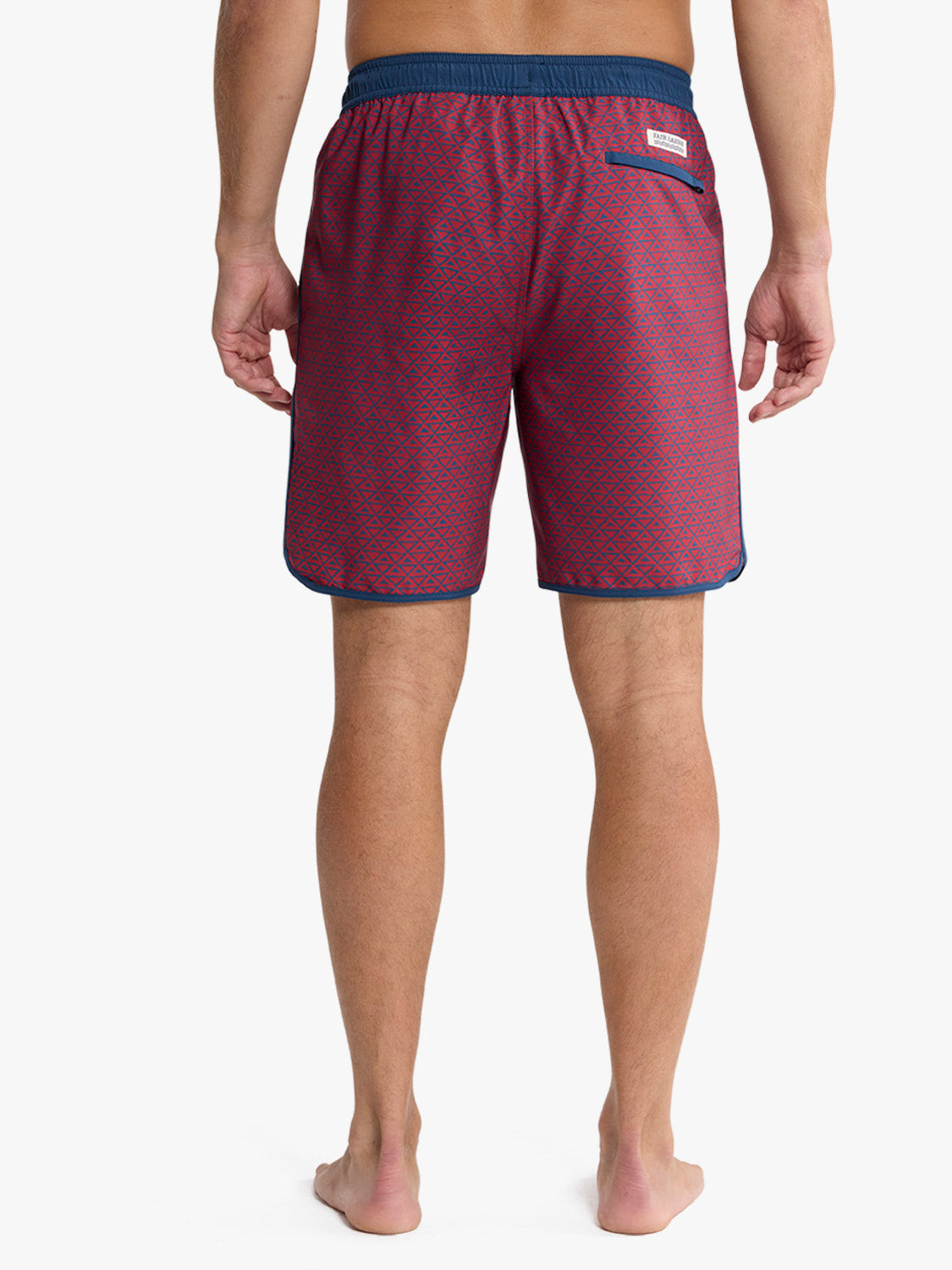 Red swim trunks with geometric pattern and navy blue waistband and trim shown from back.