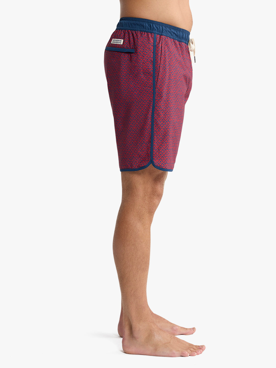 Man wearing red swim trunks with geometric pattern and blue waistband and trim.
