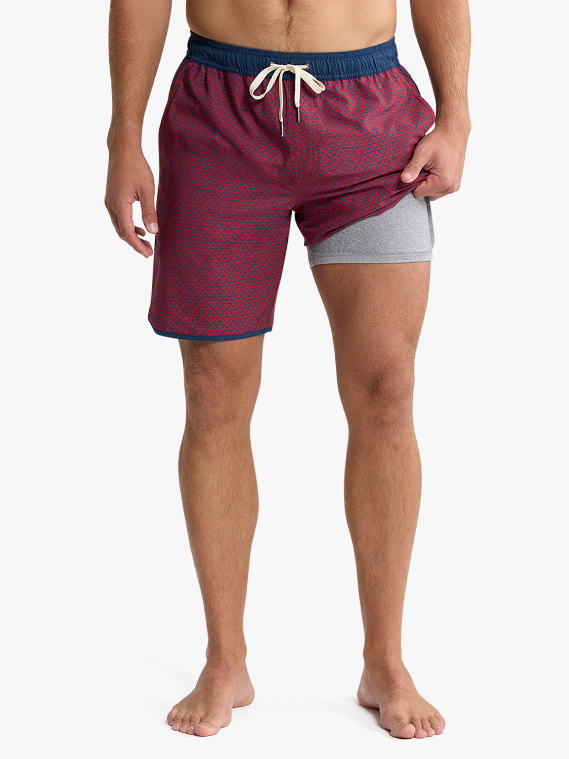 Men's swim trunks in red with geometric pattern and navy waistband with drawstring.