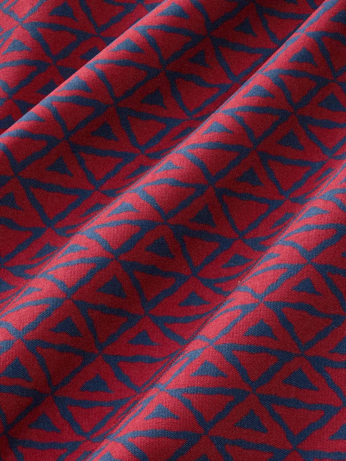 Red fabric with navy blue and light blue geometric wavy pattern creating a nautical design.