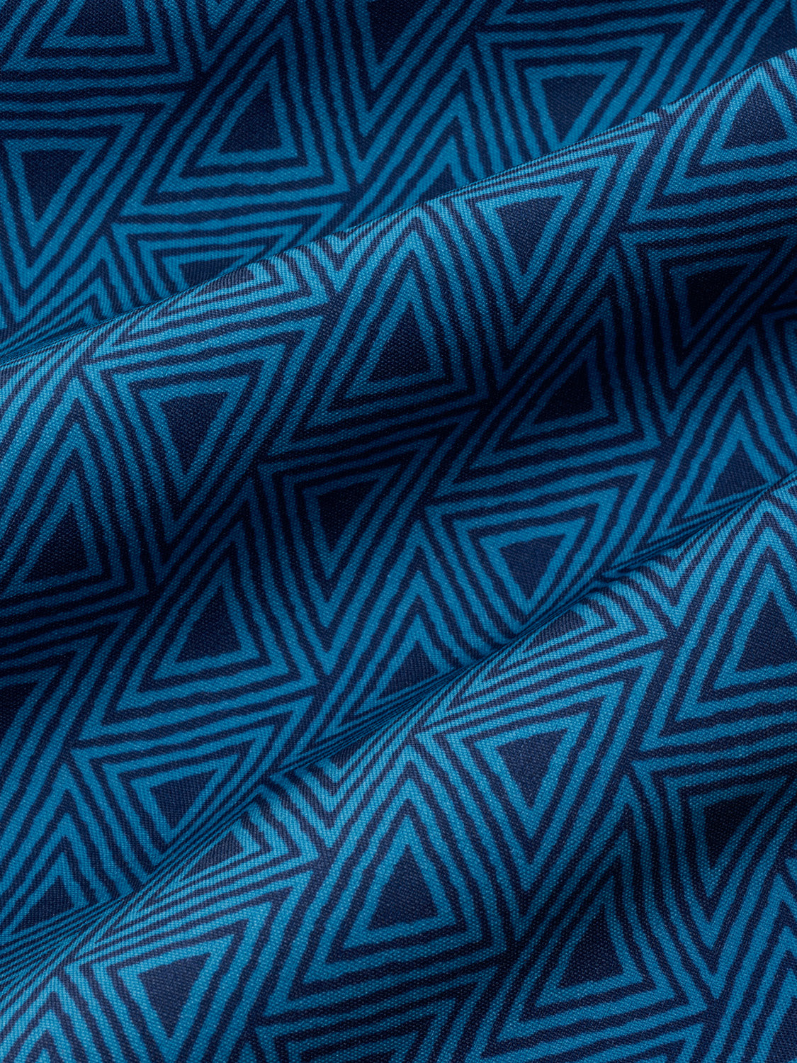 Electric blue fabric with a geometric triangular stripe pattern in varying shades of blue.
