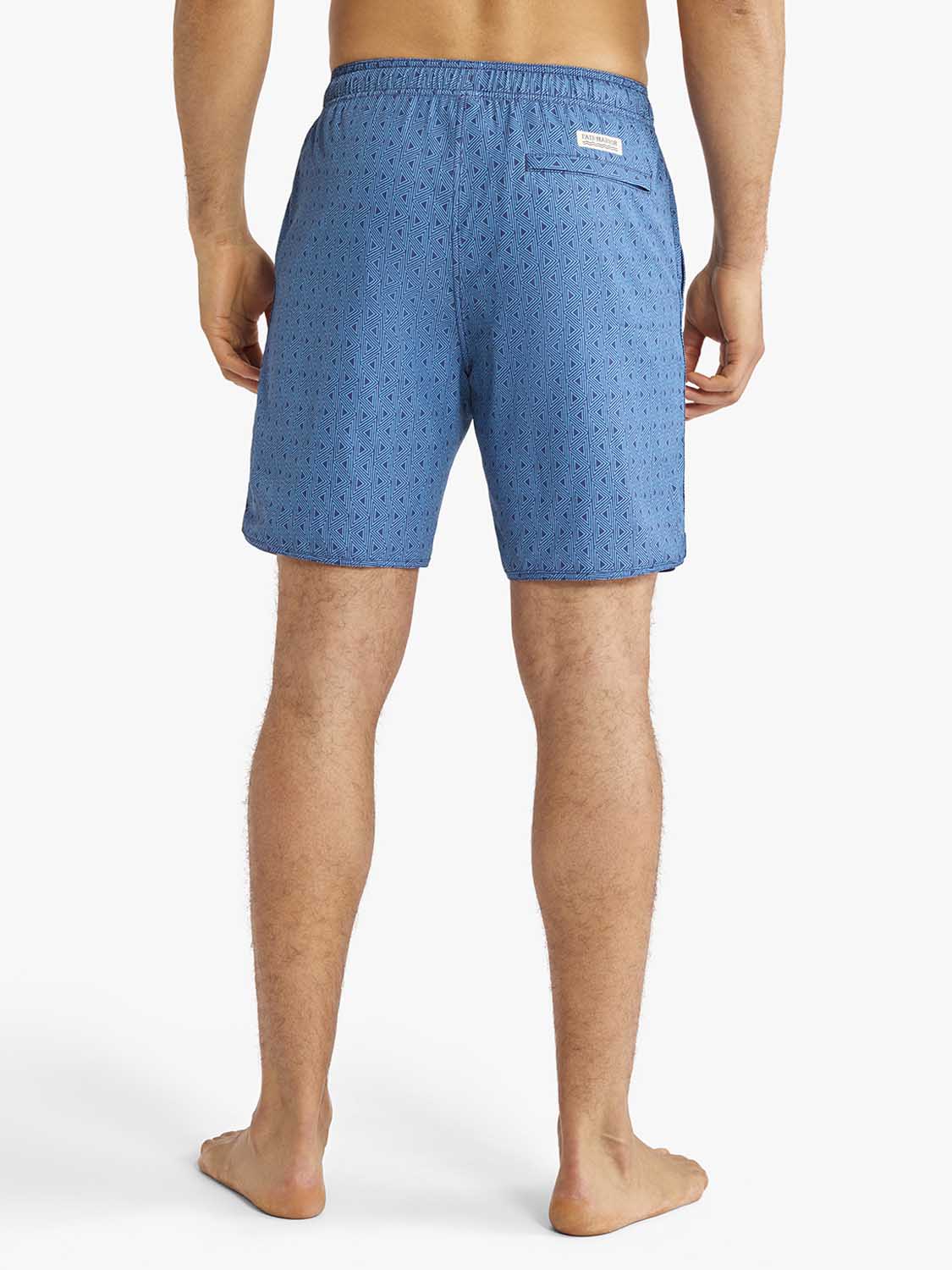 Man wearing electric blue swim trunks with small geometric anchor pattern viewed from behind.