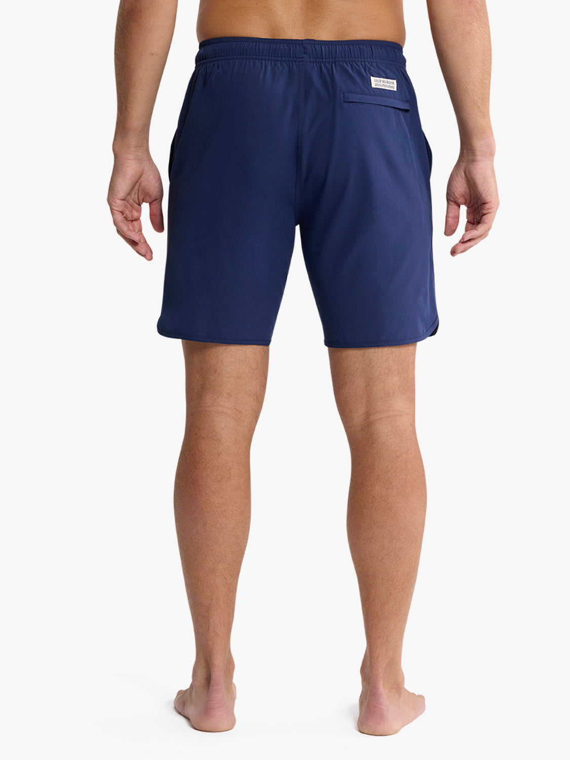 Man wearing navy swim shorts with elastic waistband and back pocket viewed from behind.