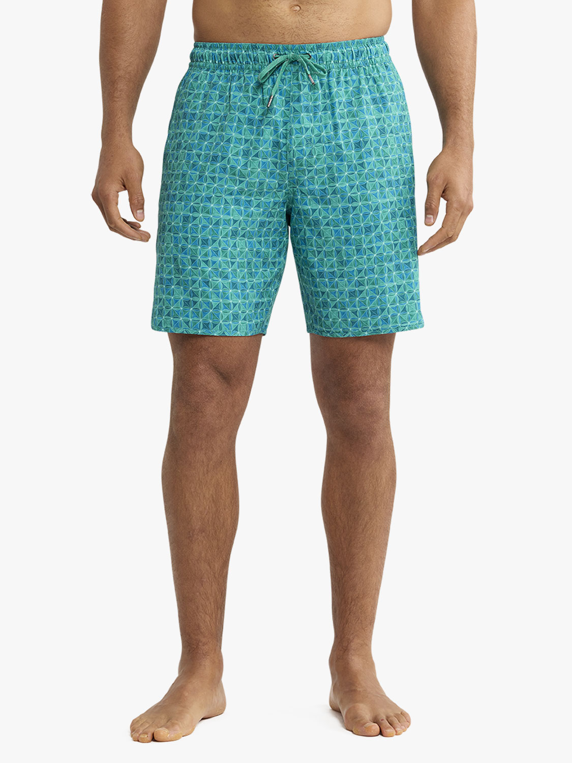 Man wearing turquoise swim shorts with a geometric tile pattern and drawstring waist.