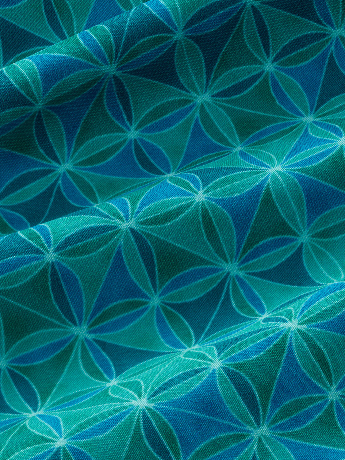 Seaglass tiled trunk fabric features repeating geometric star and anchor patterns in teal and blue tones.