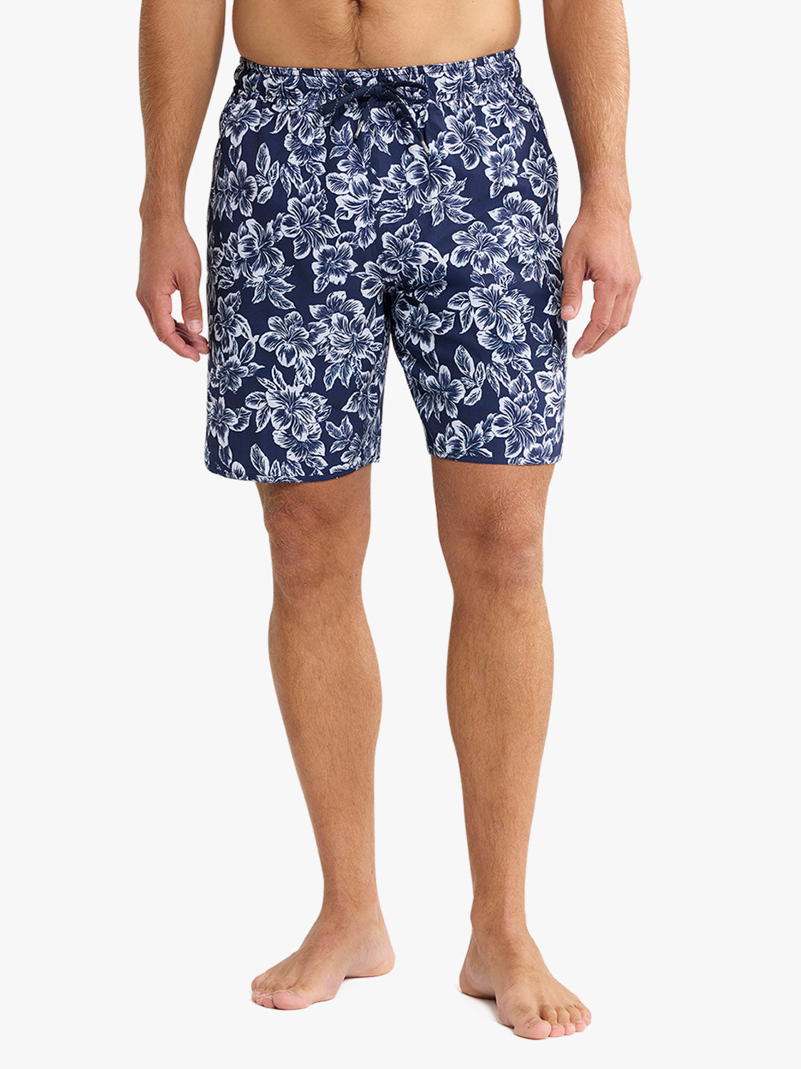 Man wearing navy swim trunk with white botanical flower and leaf pattern throughout.