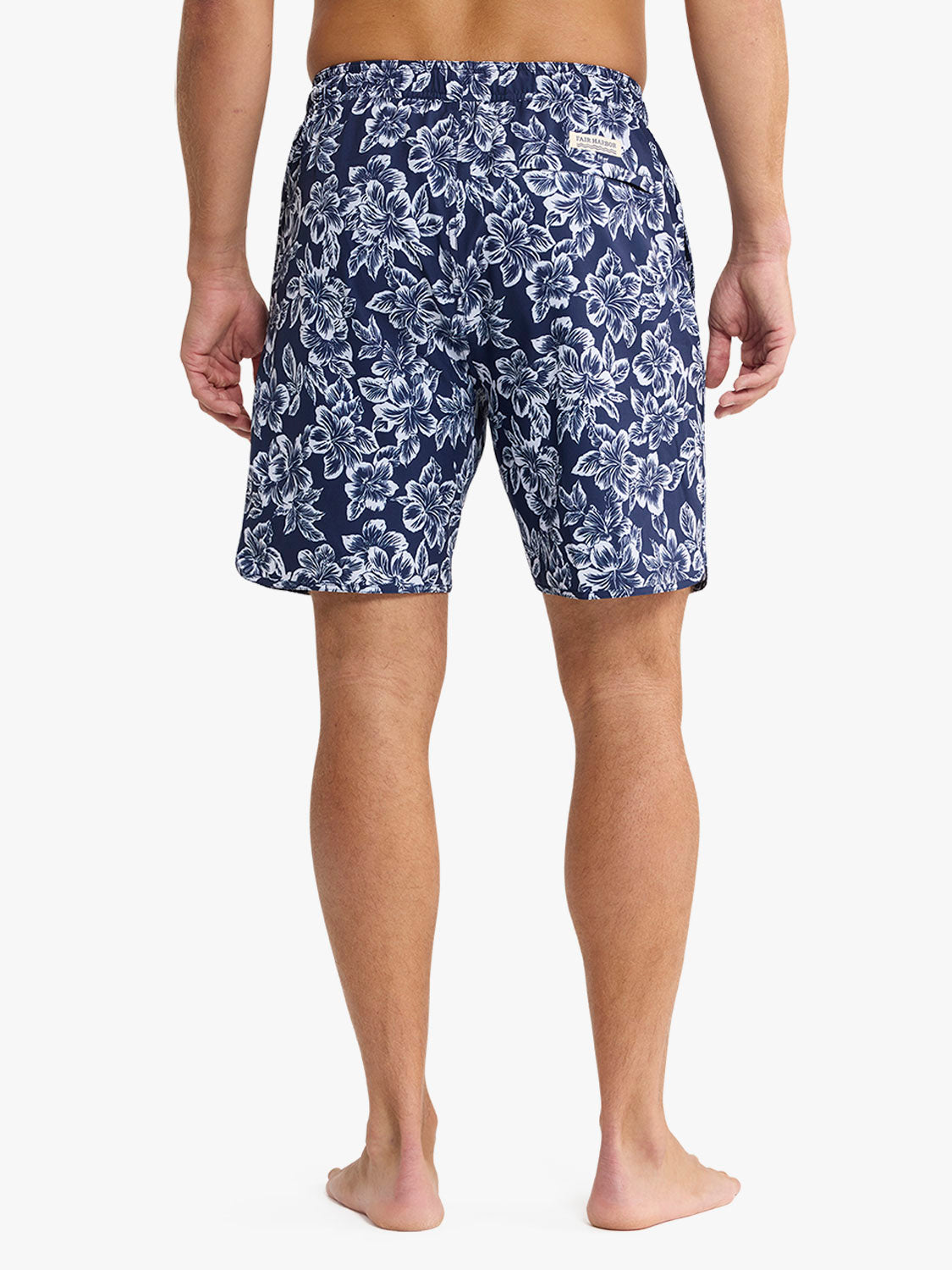 Navy swim trunks with white botanical floral print displayed on a man from waist down.