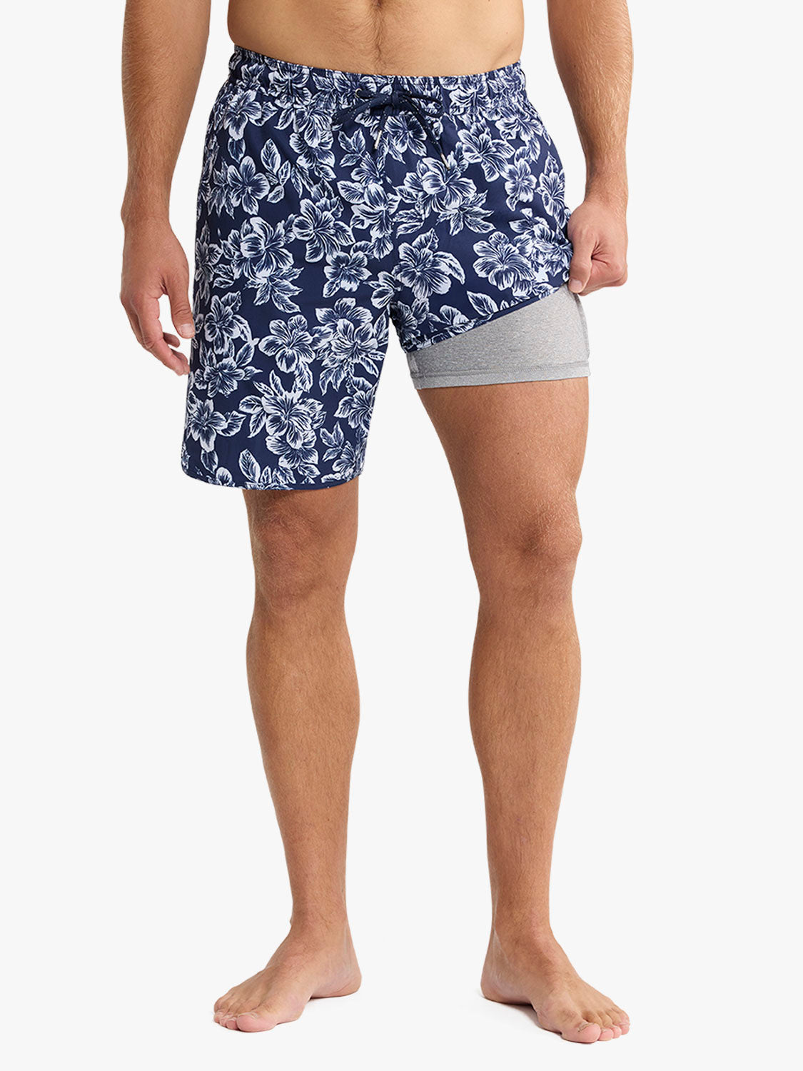 Navy swim trunks with white botanical print and gray compression shorts underneath.