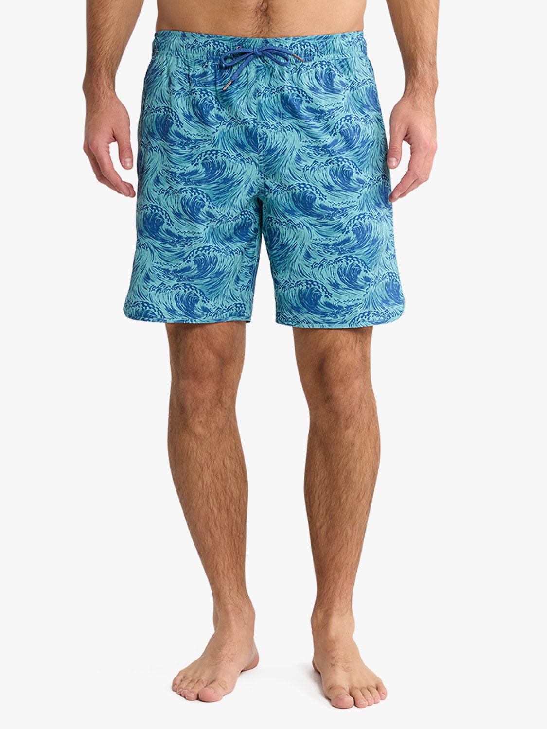 Man wearing turquoise swim trunks with dark blue wave pattern and drawstring waist.
