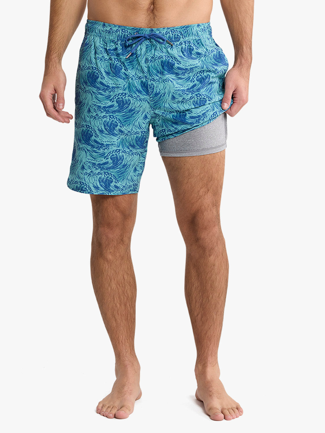 Men's swim trunks with blue wave pattern and gray compression shorts underneath.