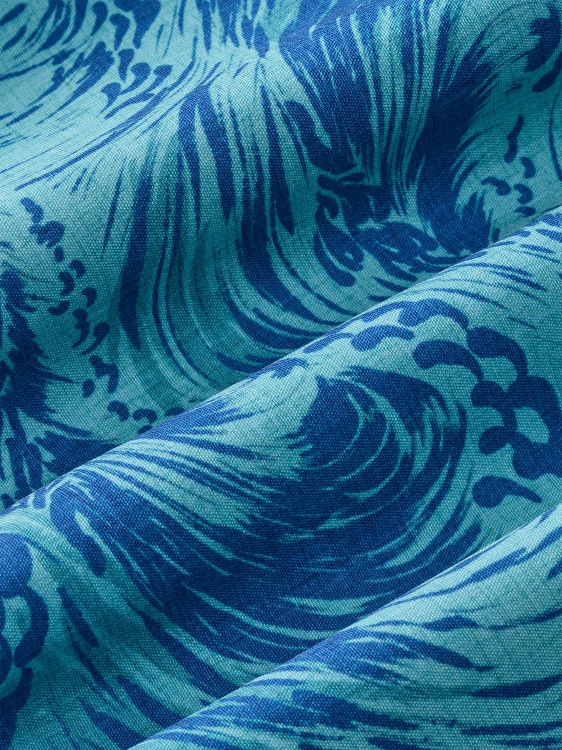 Close-up of blue and teal fabric with wave-like pattern details woven throughout.