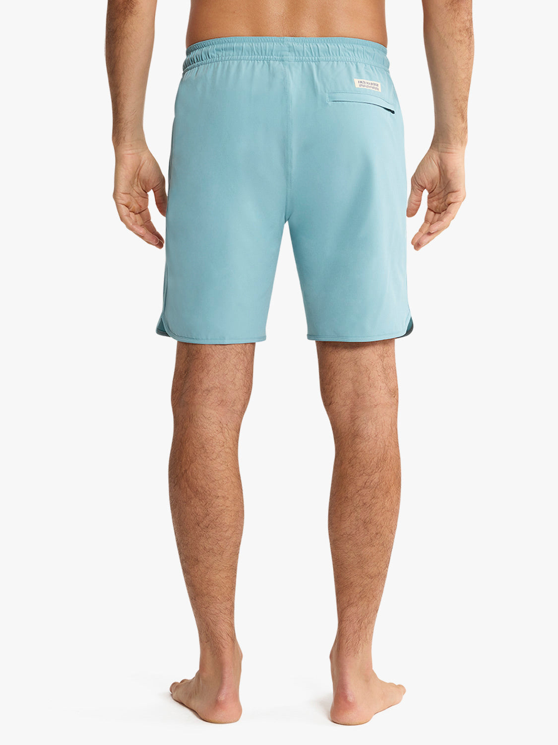 Man wearing light blue swim trunks with elastic waistband and back pocket, shown from behind.
