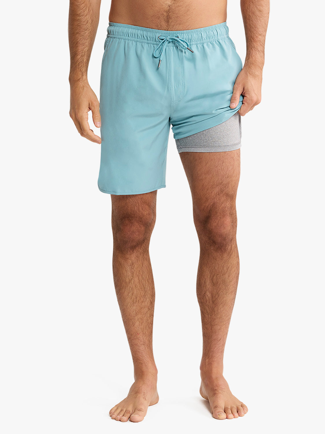 Man wearing light blue swim trunks with gray compression shorts underneath and drawstring waistband.