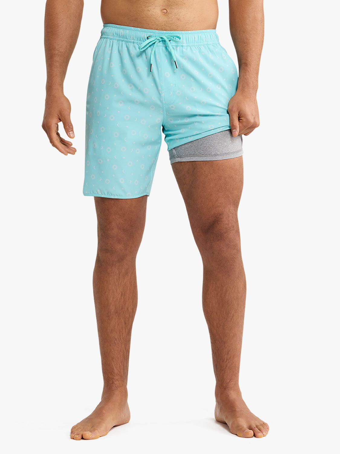 Turquoise swim shorts with small white anchor and star pattern and built-in gray mesh liner.
