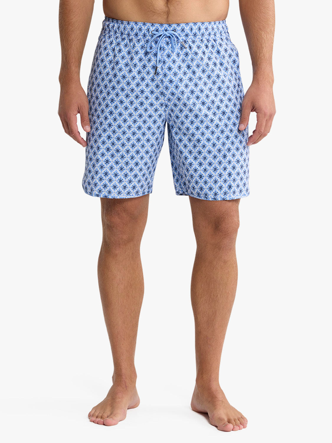 Man wearing blue swim trunks with an all-over star pattern and drawstring waist.