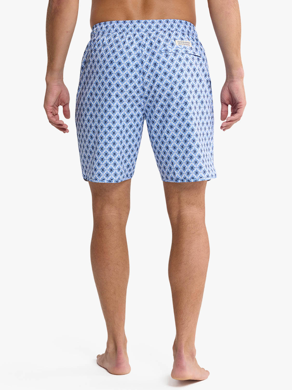 Man wearing light blue swim trunks with a dark blue star mosaic pattern throughout.