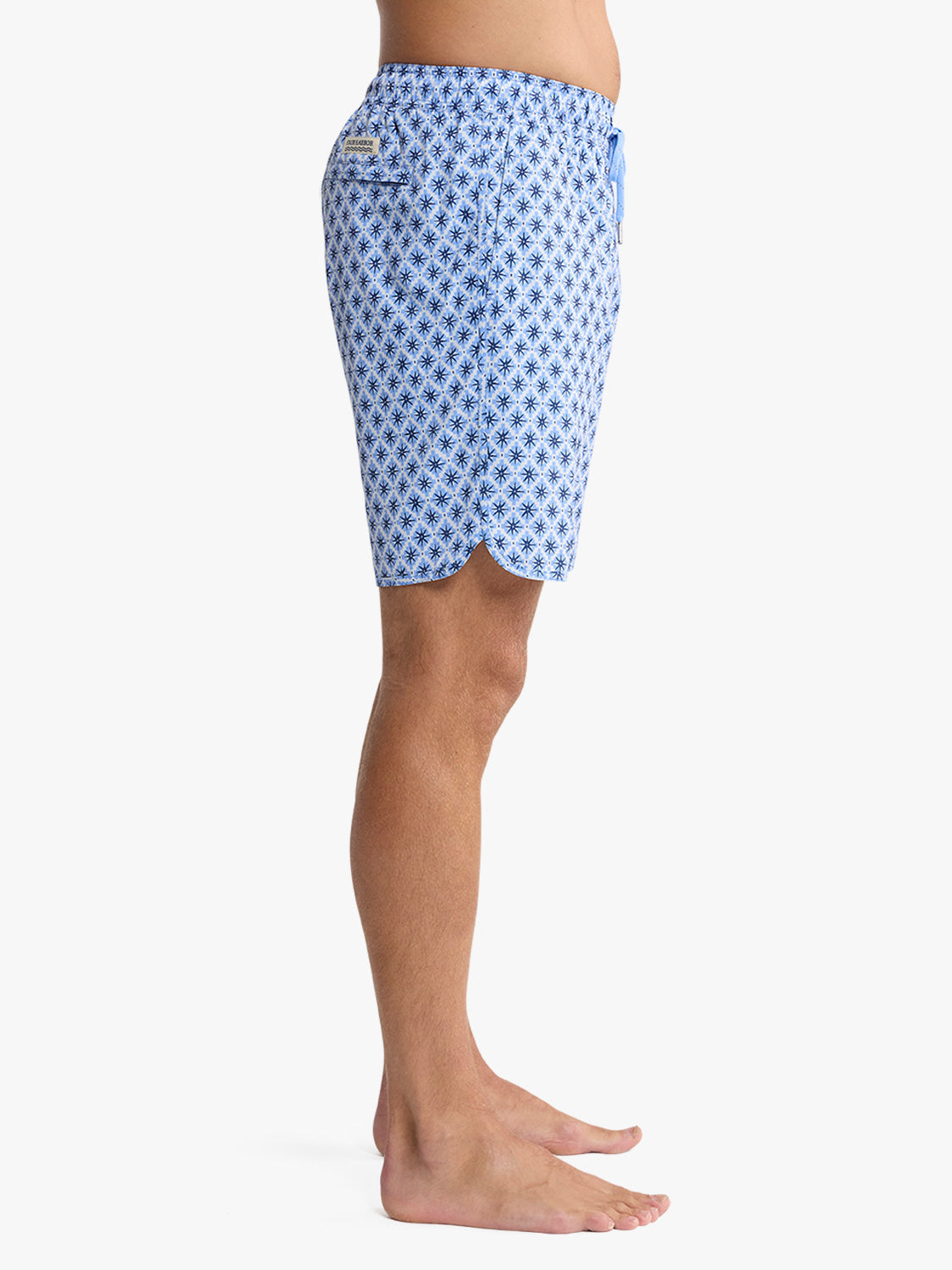 Blue swim trunk with repeating star mosaic pattern and side pocket detail worn on male model.