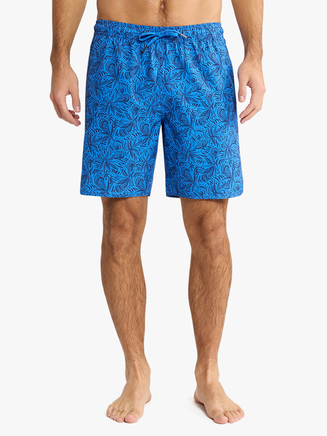 Man wearing blue swim shorts with allover leaf print pattern and drawstring waist.