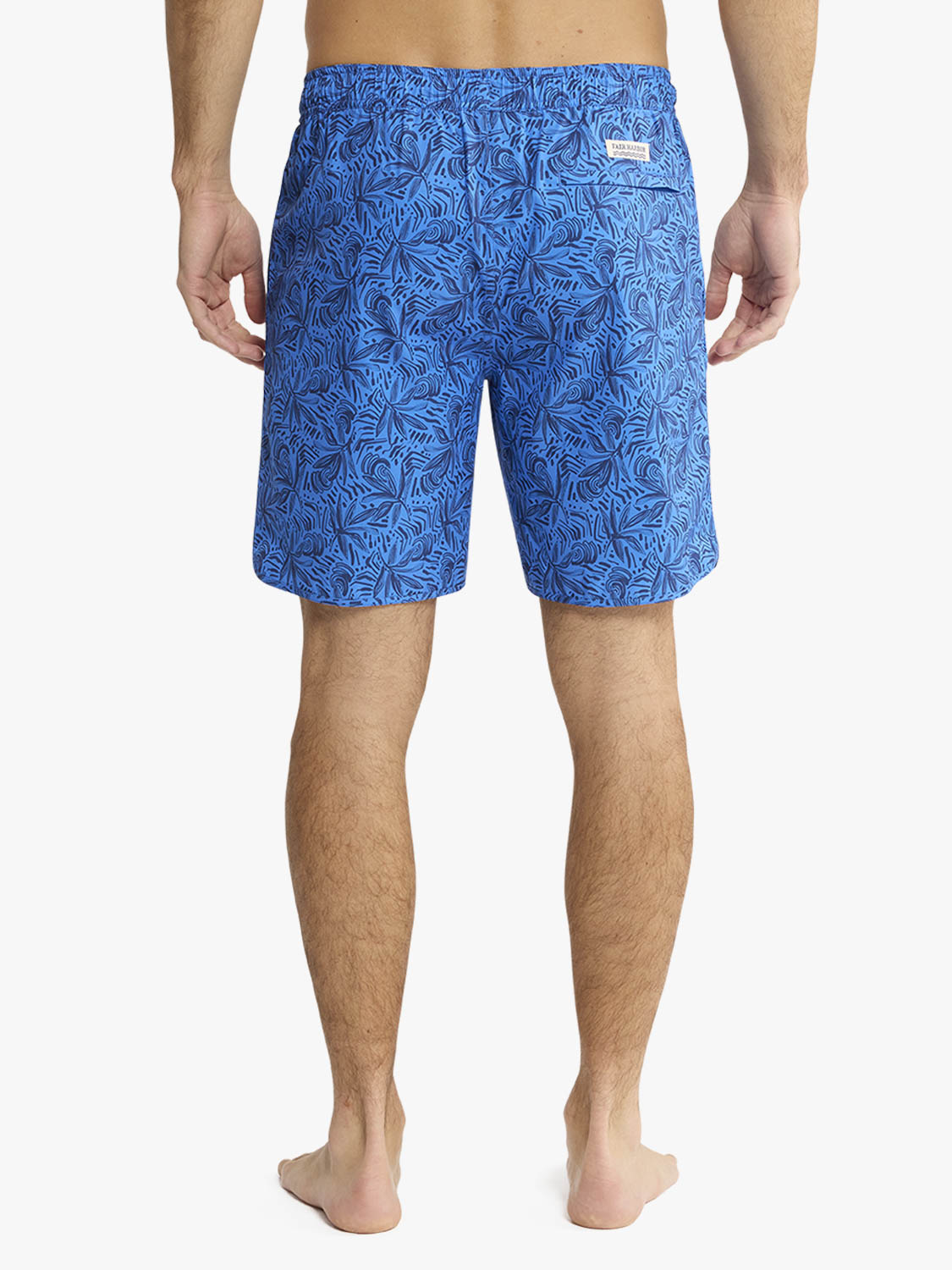 Man wearing blue swim shorts with leaf pattern shown from behind.
