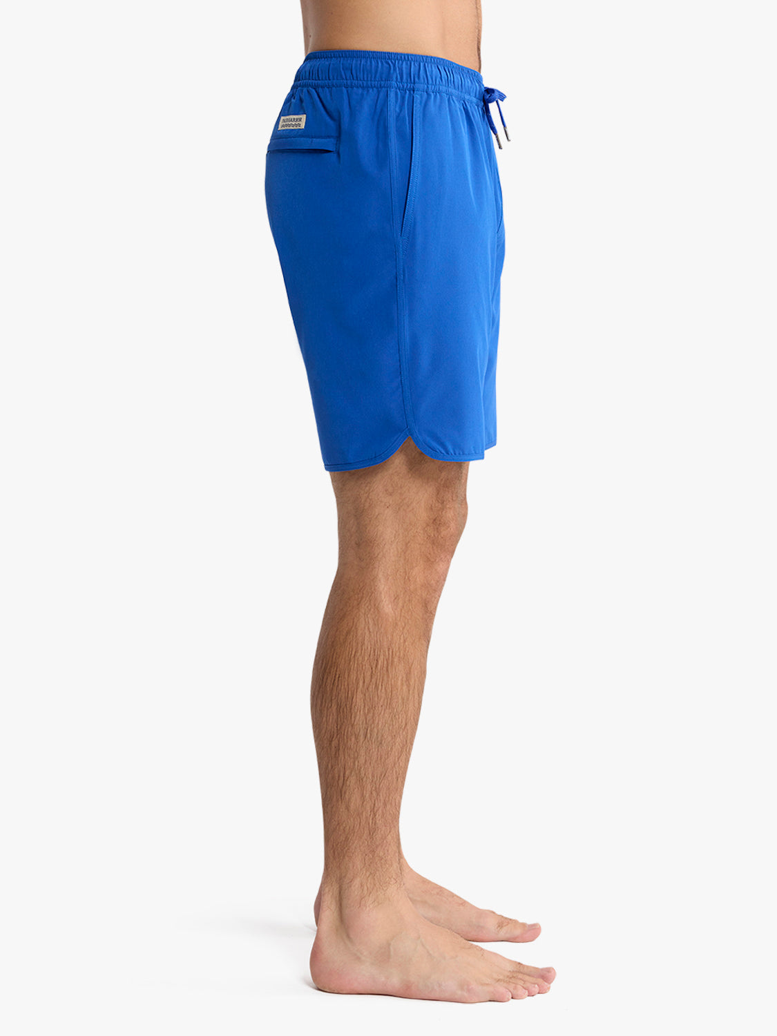 Cobalt blue swim trunk with elastic waistband and side pocket displayed on male model from waist down.