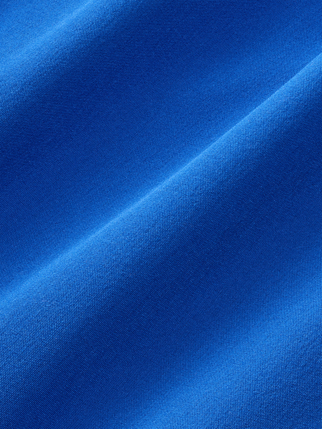 Cobalt blue fabric with a woven texture and diagonal fold creating light and shadow contrast.