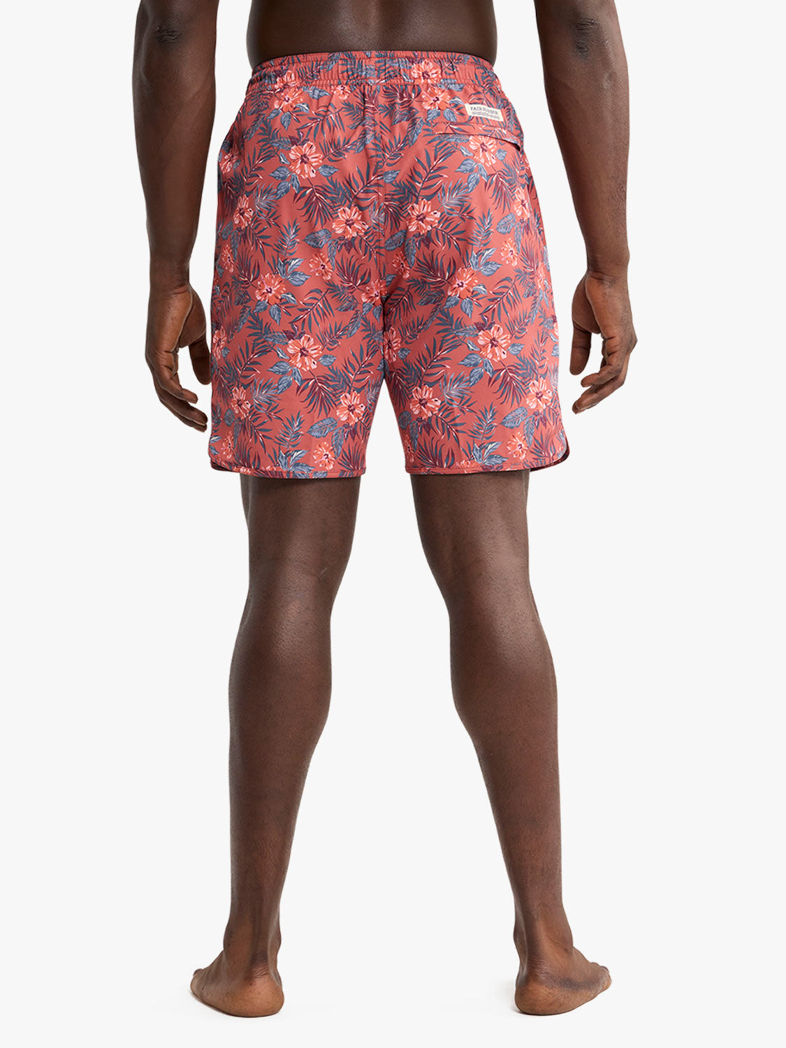 Man wearing red swim trunks with blue and coral tropical floral pattern shown from behind.
