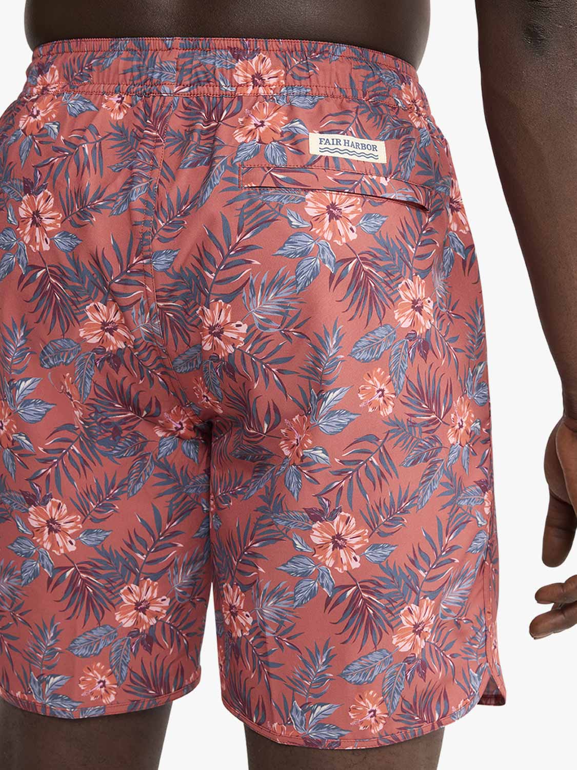 Red swim shorts with blue and white floral print and Fair Harbor brand label visible.