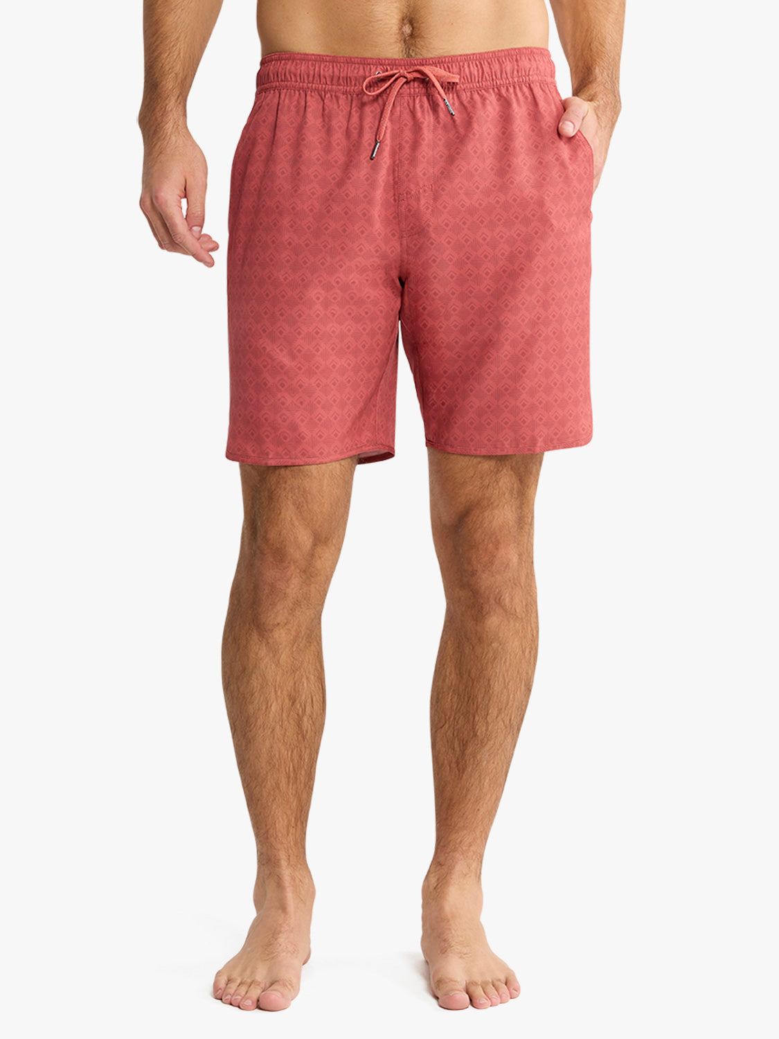 Man wearing red tile patterned swim trunks with drawstring waist and side pockets.