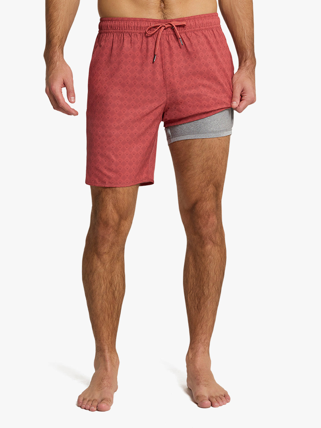 Man wearing red tile-patterned swim trunks with gray undershorts and drawstring waistband.