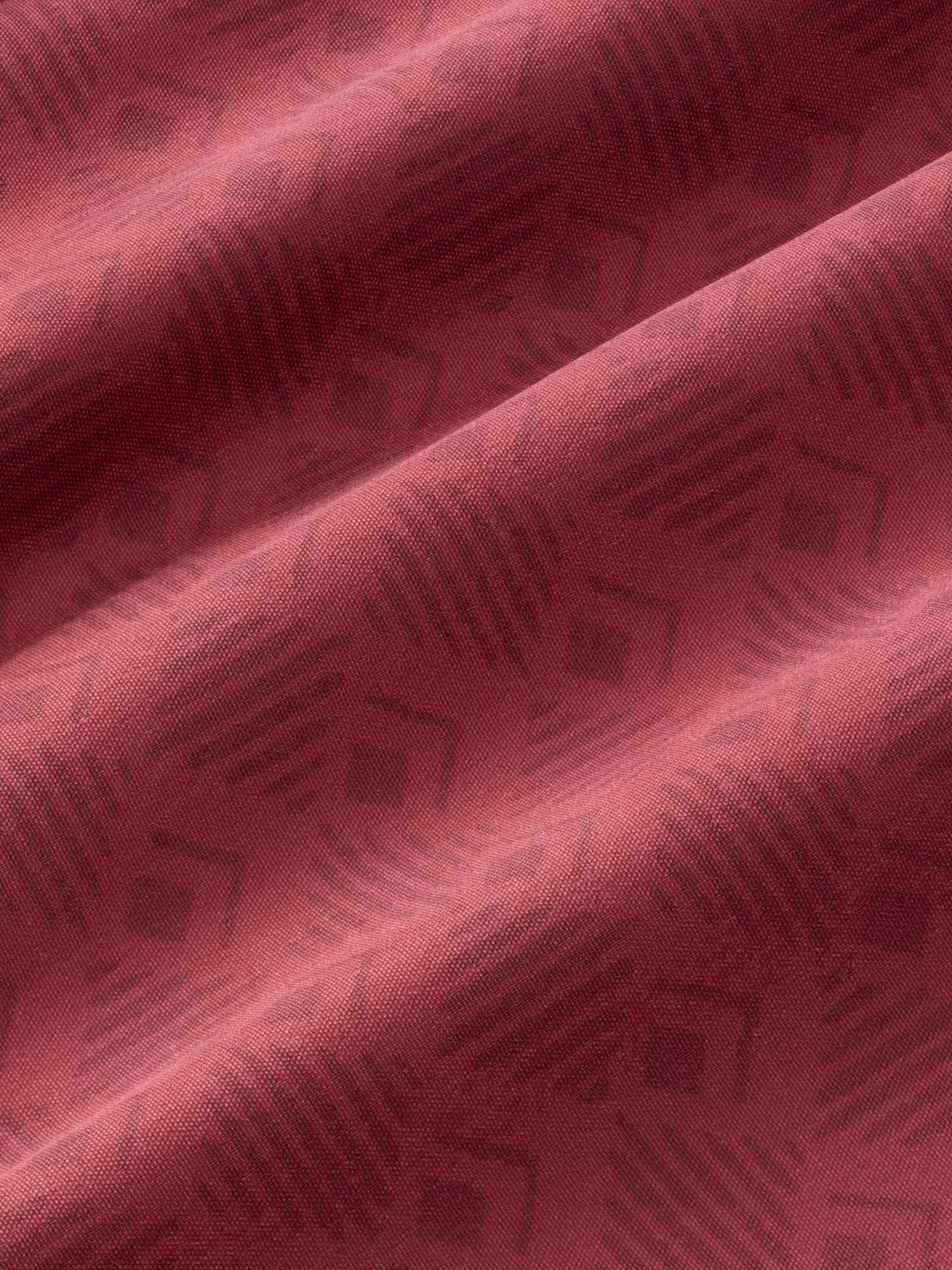 Close-up of red textured fabric with diagonal folds and woven surface detail.