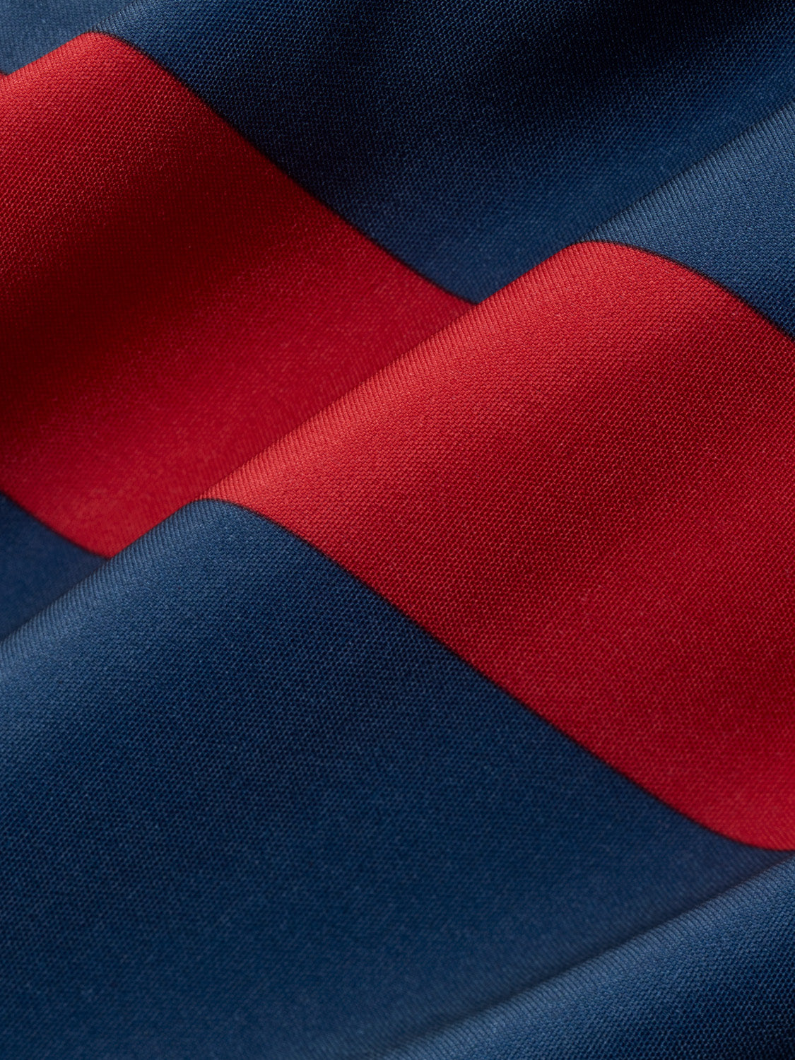 Red and navy blue striped swim trunk fabric with textured weave detail displayed flat.