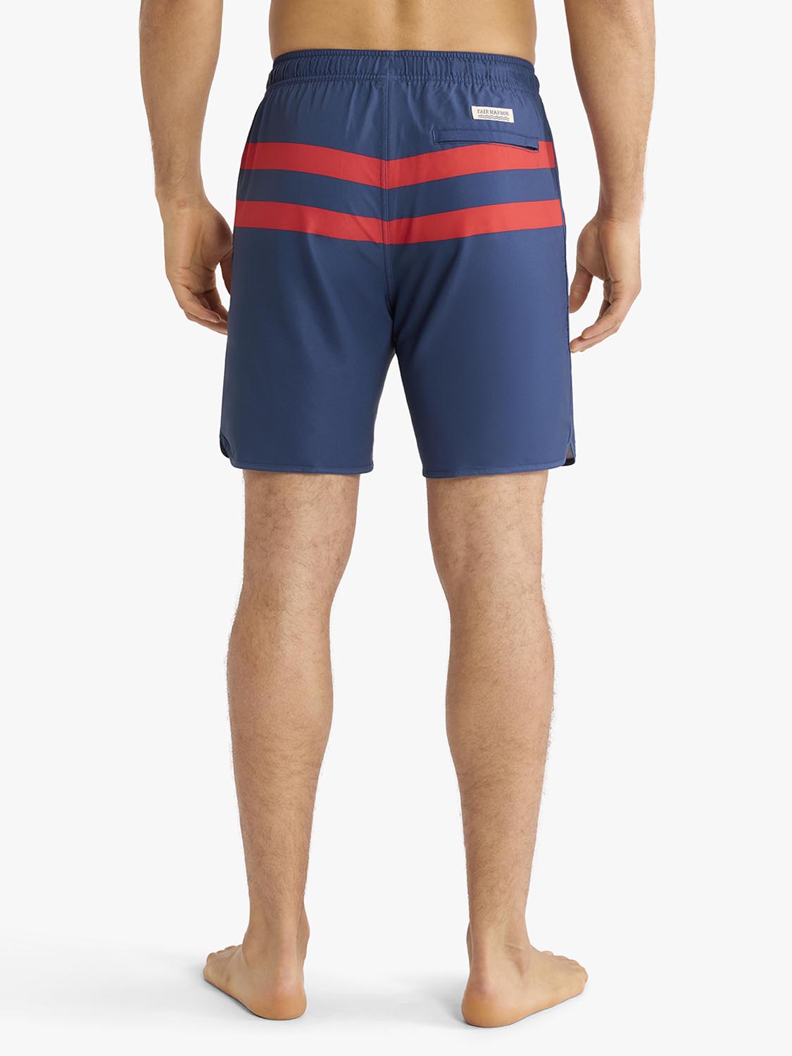 Man wearing navy swim trunks with two red horizontal stripes across the back.