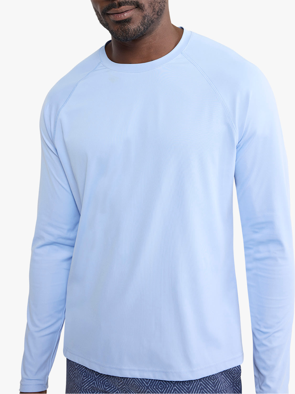 Man wearing a light blue long-sleeve rashguard with a crew neckline and raglan sleeves.