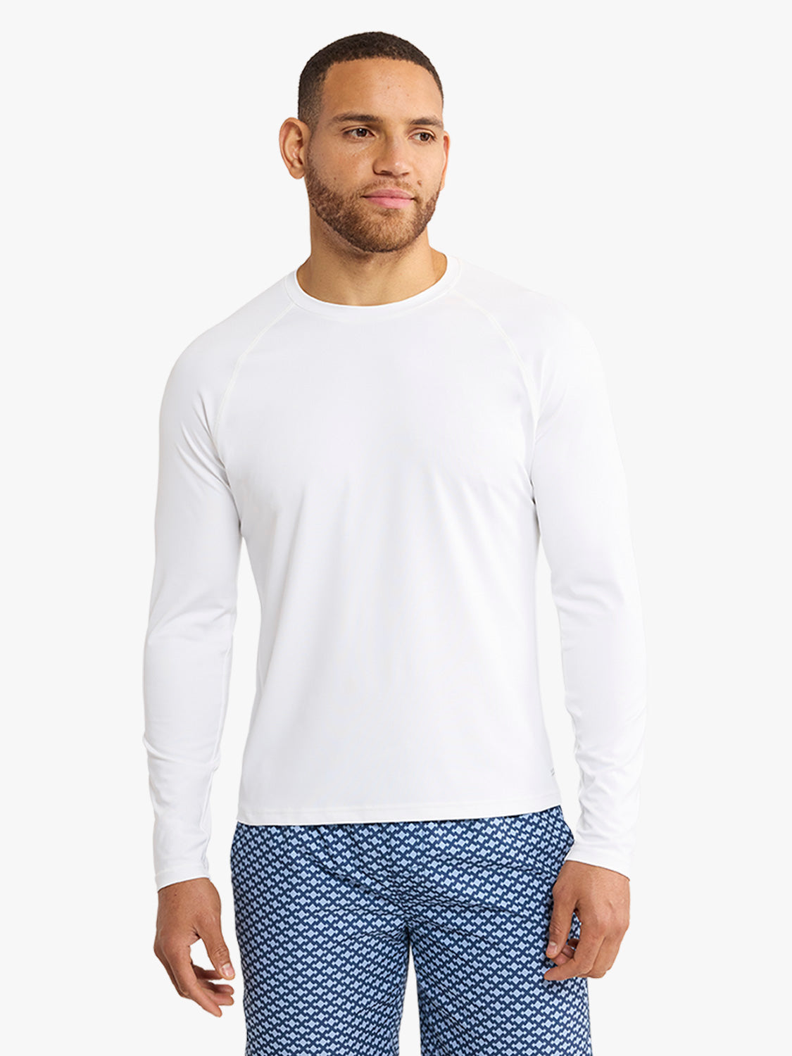 Man wearing a white long-sleeve rashguard with a crew neckline and fitted sleeves.