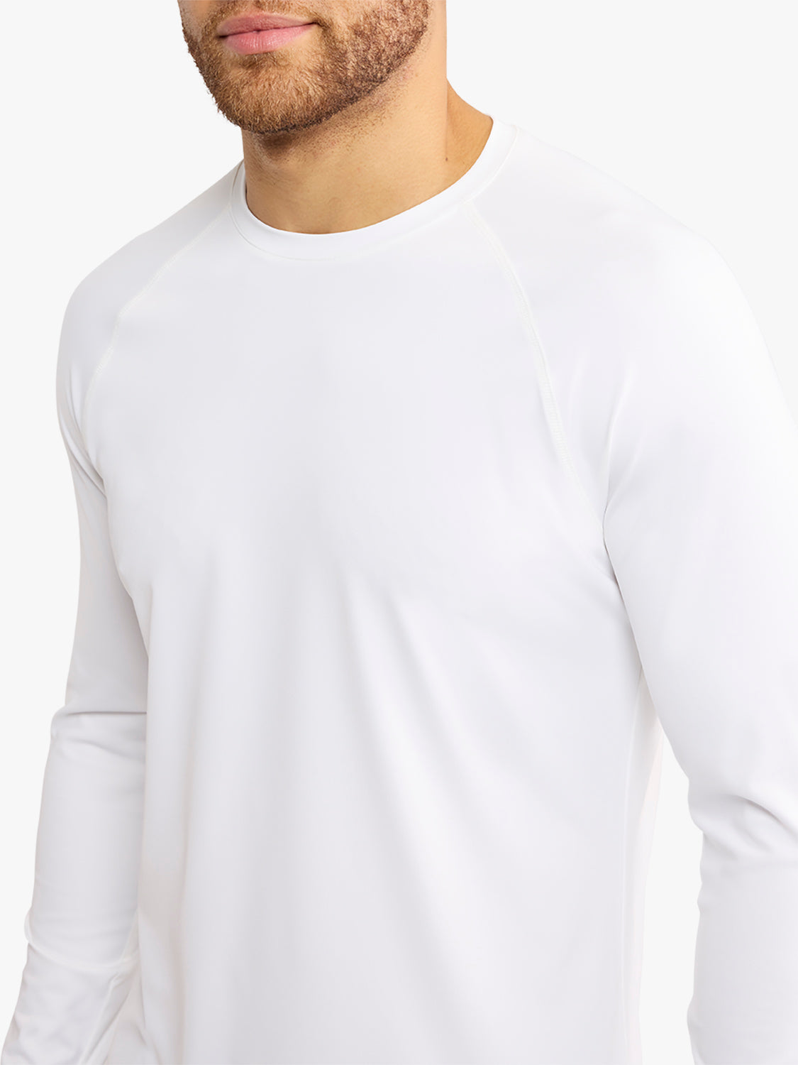 Man wearing a white long-sleeved rashguard with a crew neckline and fitted sleeves.