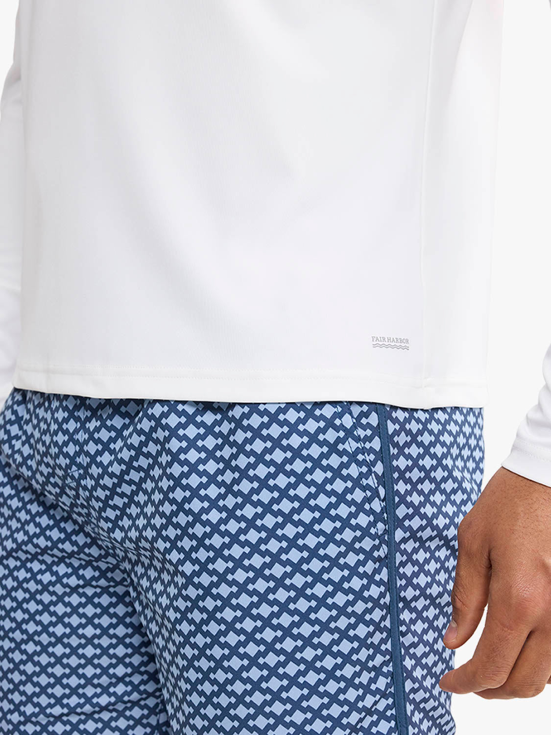 White long-sleeve rashguard with small anchor logo on chest and geometric patterned swim trunks.