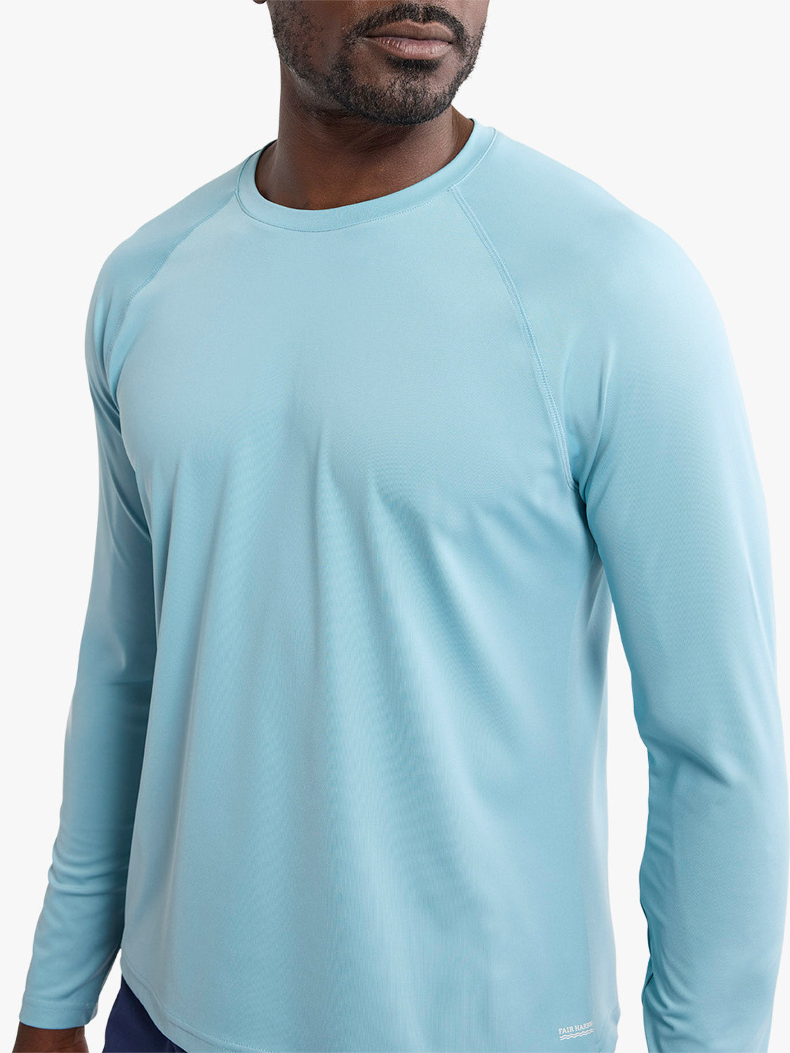 Man wearing a light blue long-sleeve rashguard with a crew neckline and raglan sleeves.