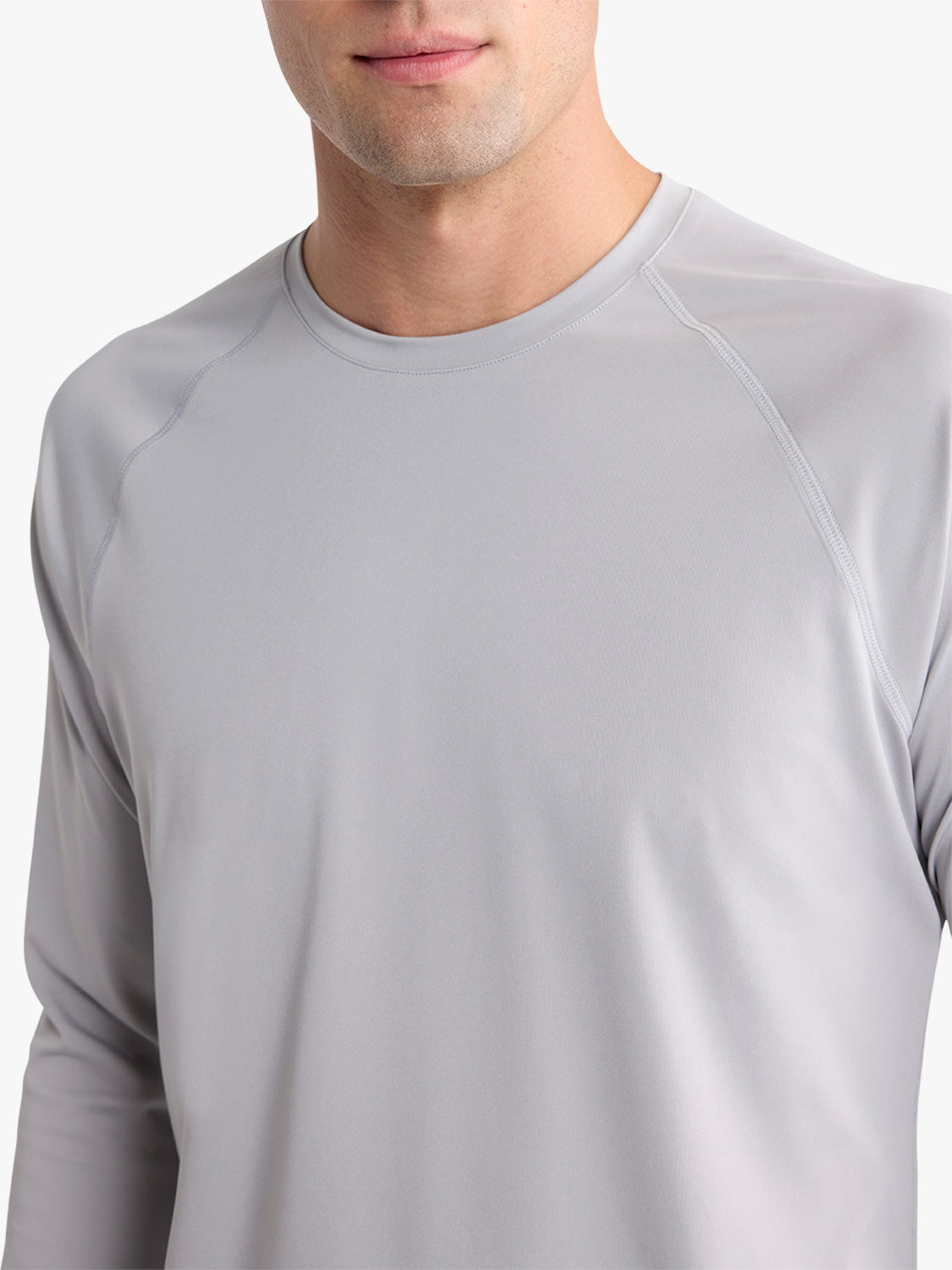 Man wearing a light gray long-sleeve rashguard with a crew neckline and contrasting seams.
