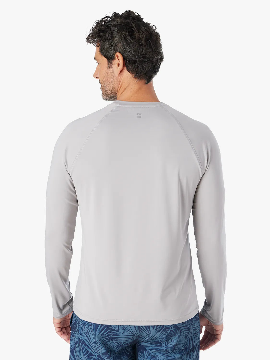 Man wearing a grey long-sleeved rashguard with raglan sleeves, shown from the back view.